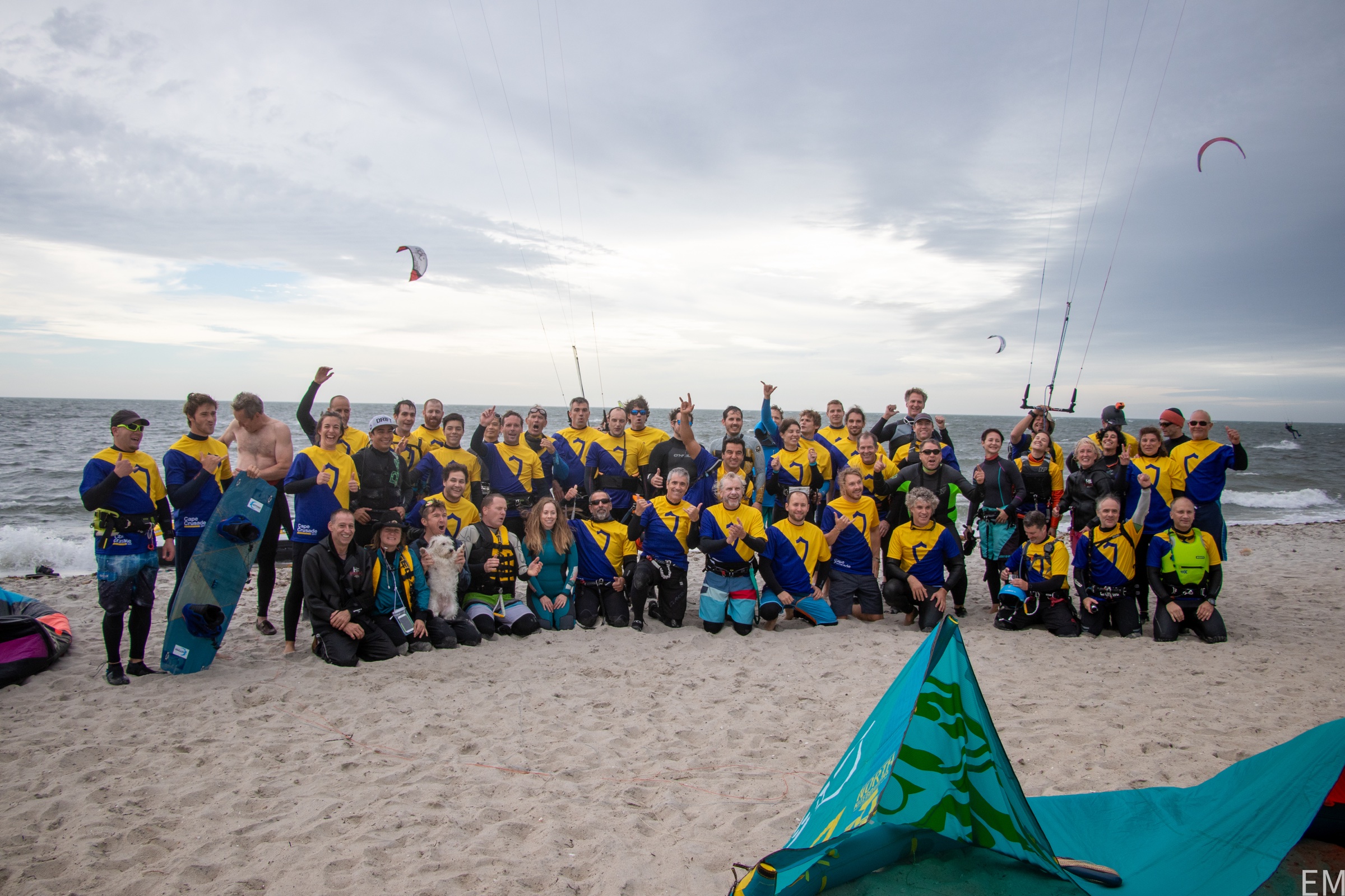 MassKiting riders gathered together on a beach after a kiteboarding session